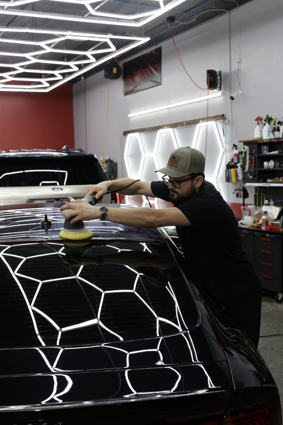 Technician machine polishing an Audi RS7 under hex lights