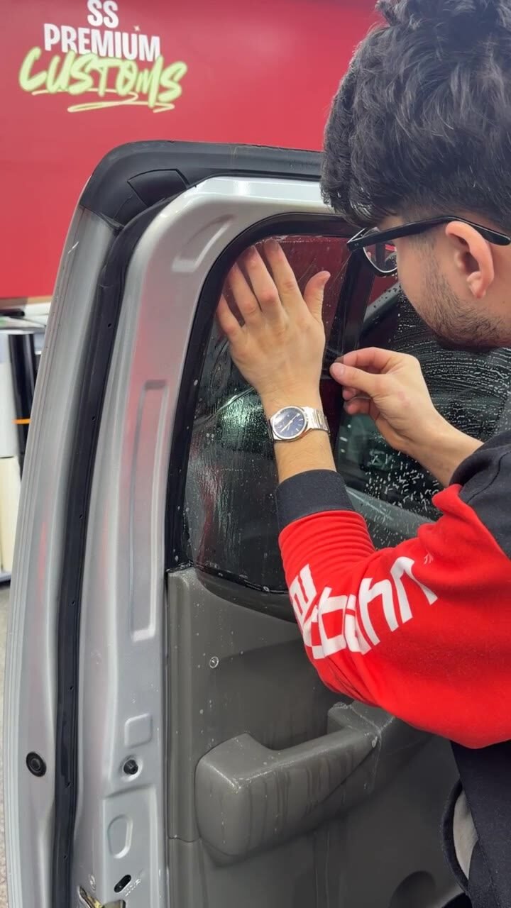 Installer applying ceramic window tint on a truck door in the SS Premium Customs studio